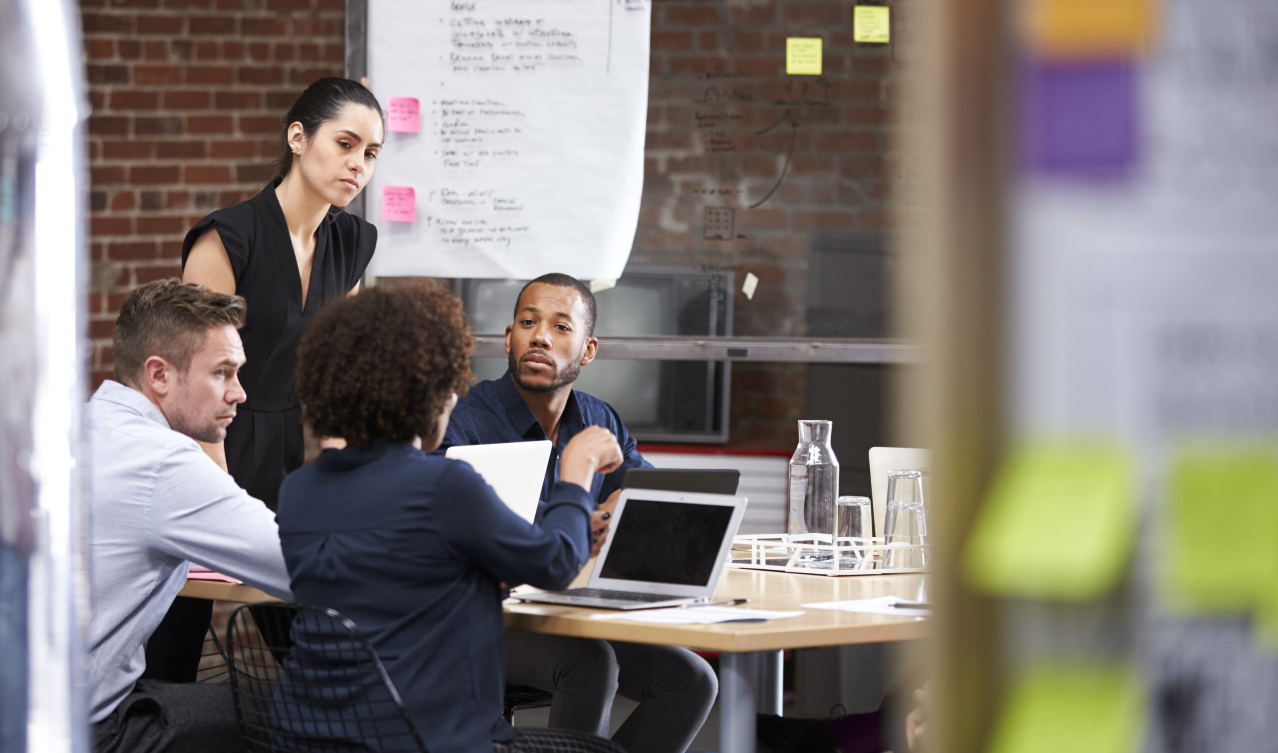 Young Businesswoman Standing And Leading Office Meeting Around Table