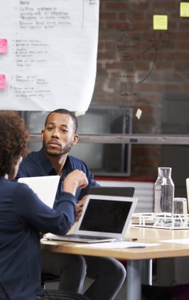Young Businesswoman Standing And Leading Office Meeting Around Table